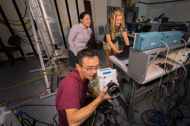 Dr. Ikeda-Gilbert instructs undergraduate AOE student, Rebecca Keller, and graduate AOE student, Zhongshu Ren on how to properly focus one of two high-speed Phantom VEO 710S cameras in preparation for a flexible wedge drop test.